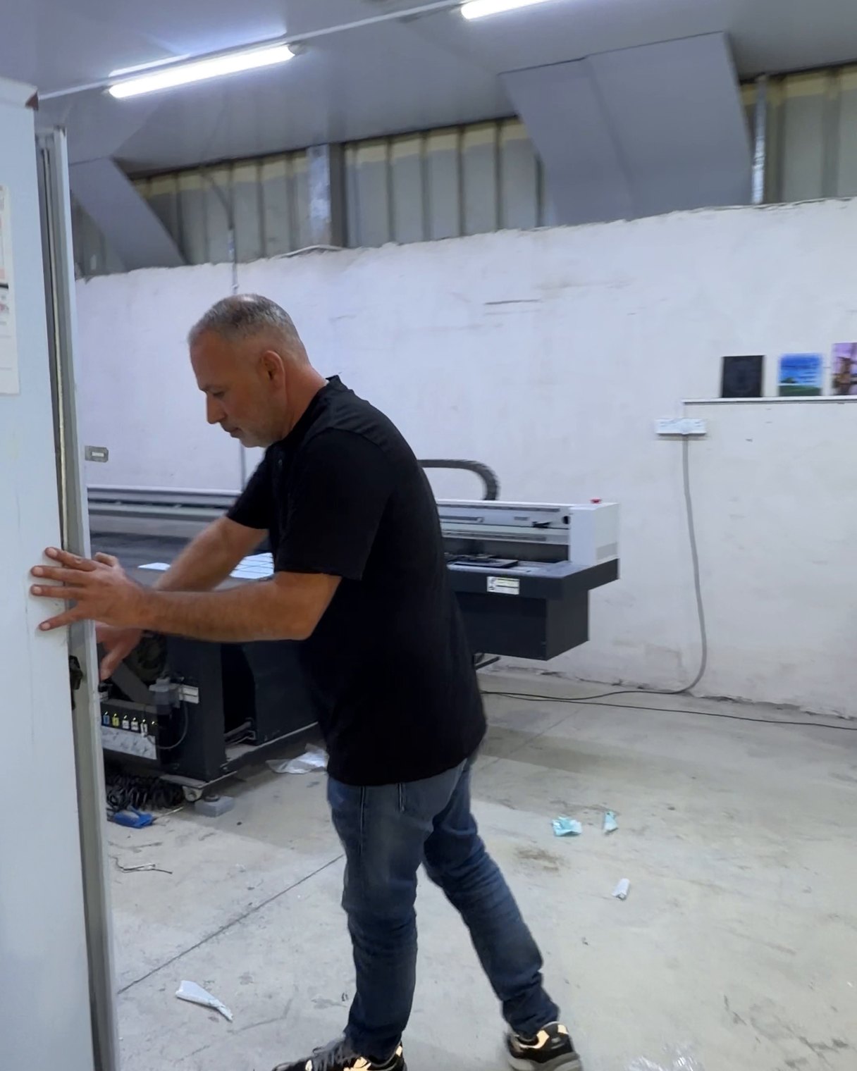 חמיק מזור מזיז לוח לבן גבוה ליד מדפסת שטוחה במפעל השילוט